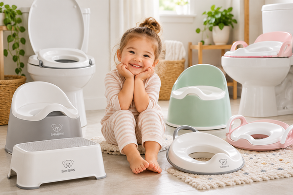 A happy toddler sits in a bright bathroom surrounded by potty training seats, step stools, and toddler-friendly essentials.