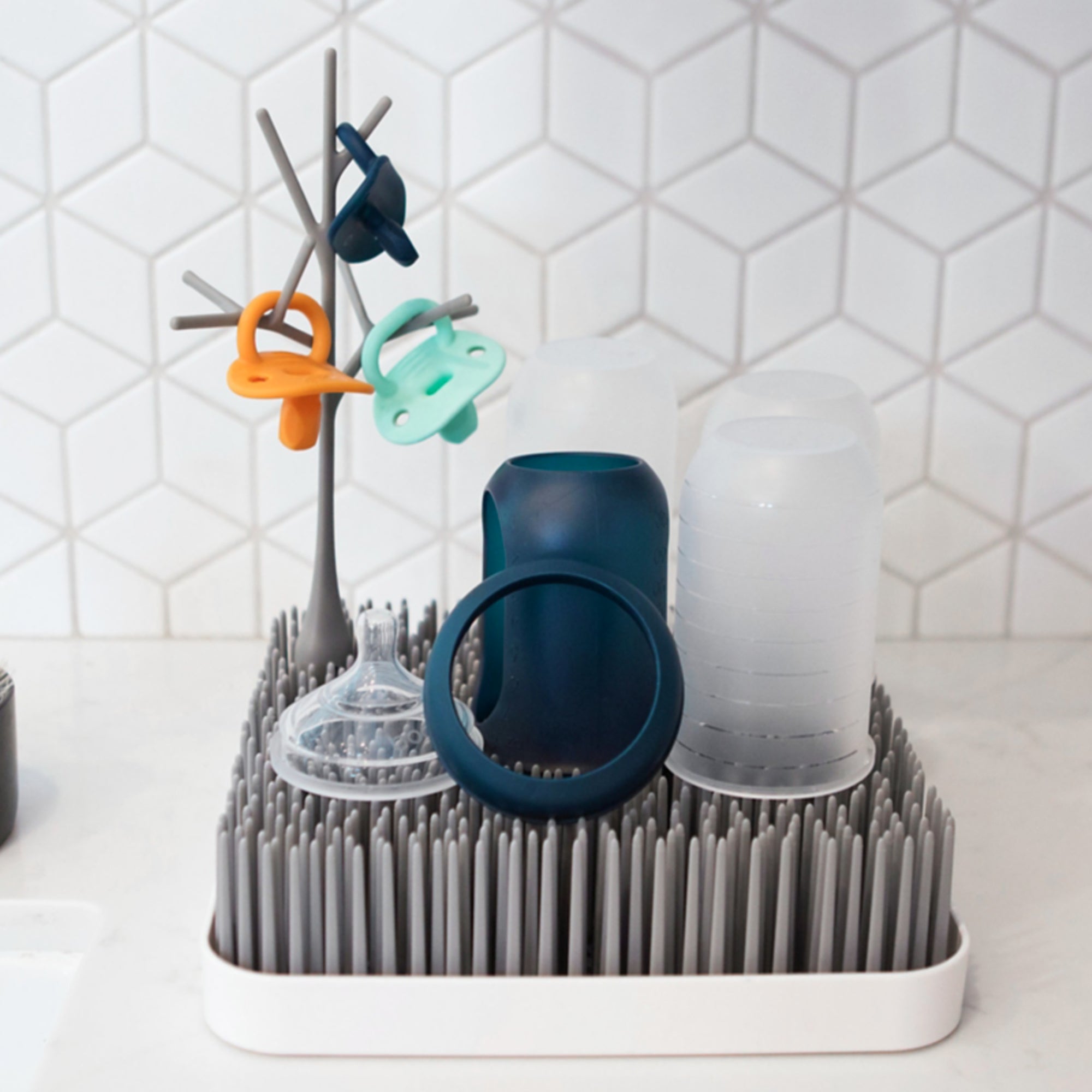Boon Grass drying rack holding baby bottles and pacifiers upright for fast, hygienic air drying.