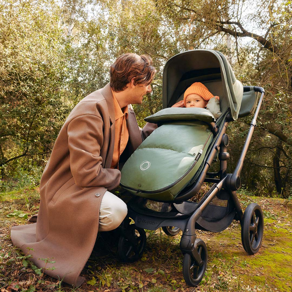 Bugaboo footmuff on stroller keeps baby warm and cozy while dad enjoys a relaxed walk together in the park.  