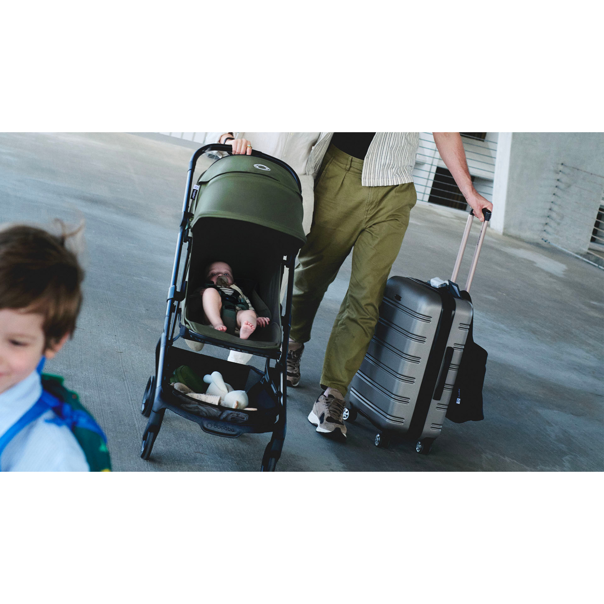 Parent walking through airport with infant in compact travel stroller and rolling suitcase, highlighting lightweight, airplane-ready stroller design.