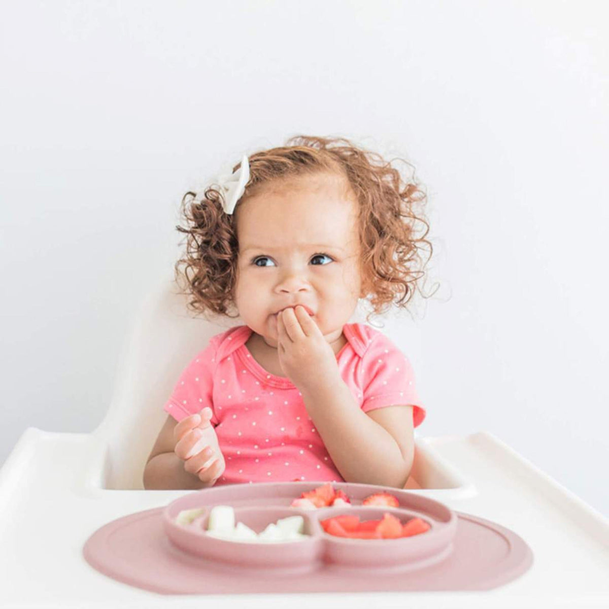 Baby enjoying her meal using the EZPZ Mini Mat during baby-led weaning.