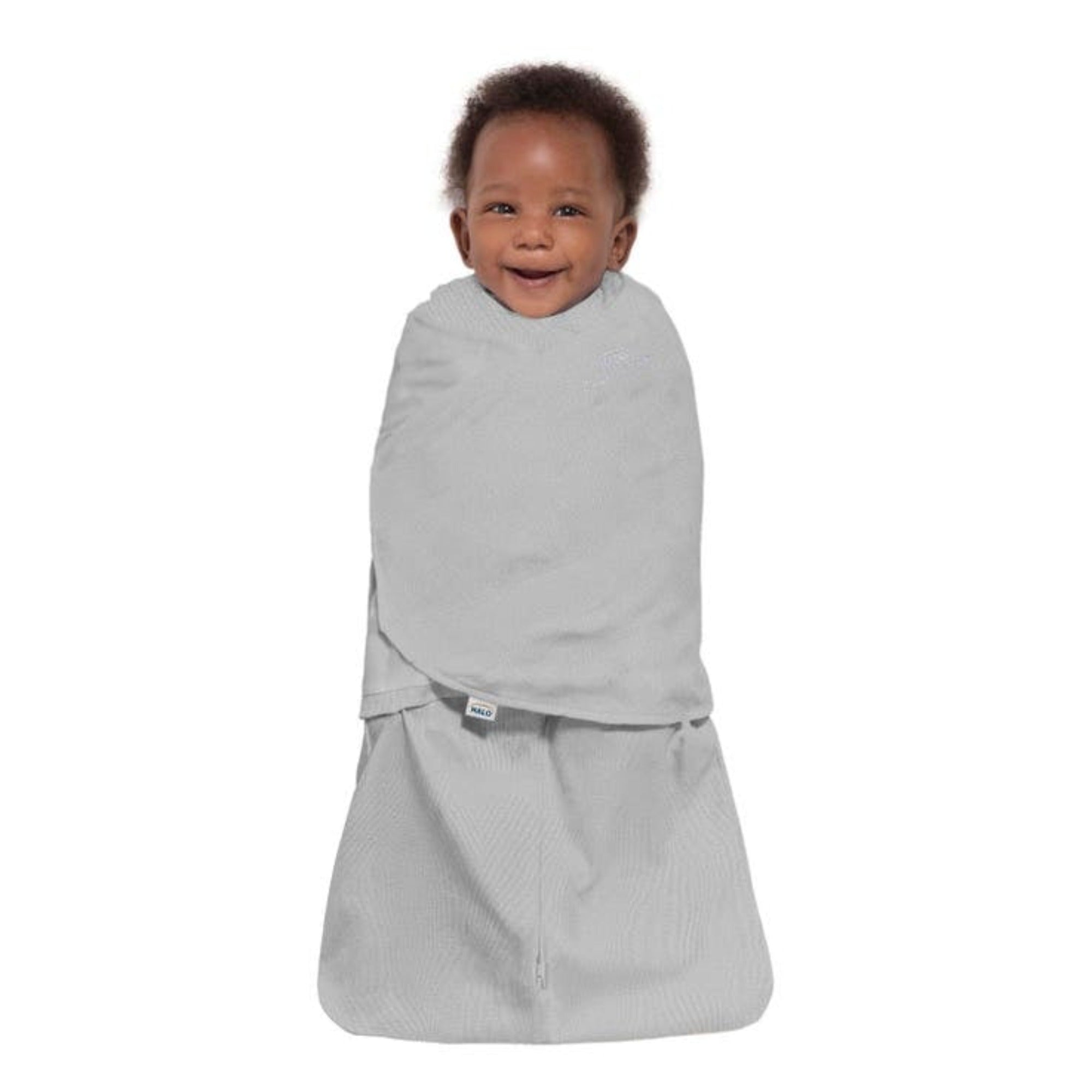 Smiling baby resting comfortably in a Halo SleepSack, cozy and secure for calm, happy, and peaceful sleep. 