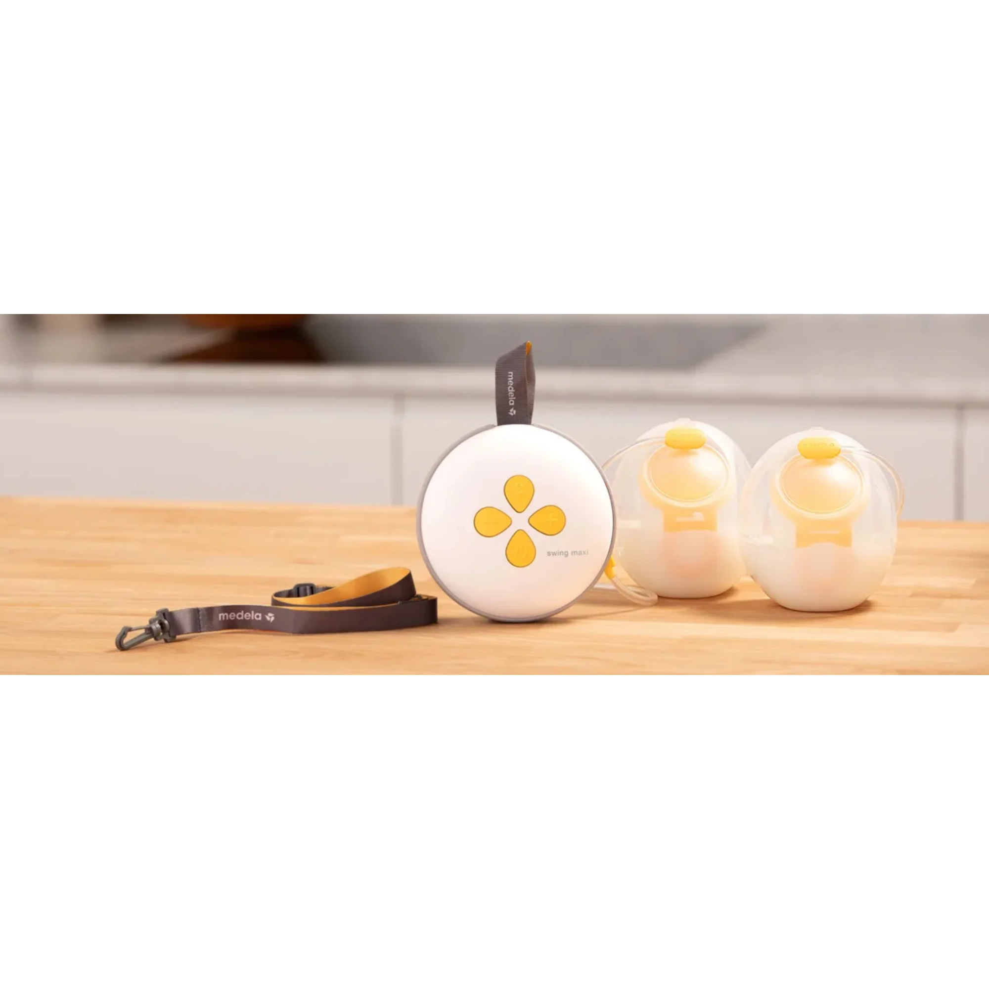Medela Swing Maxi Hands-Free Double Breast Pump displayed on a table, showing its compact design and pumping parts.