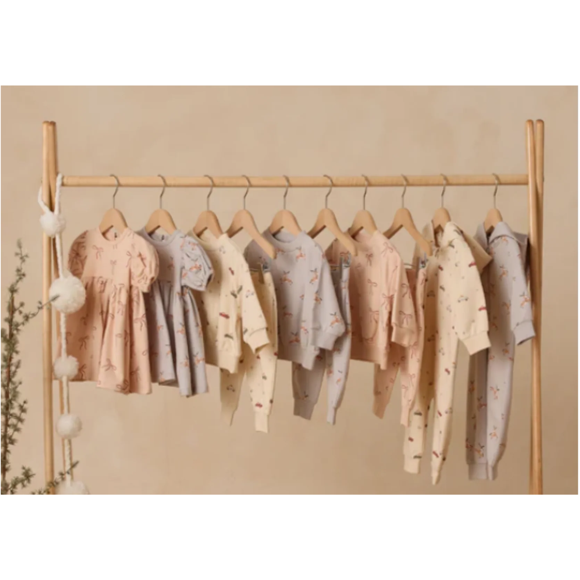 Quincy Mae baby clothing collection hanging on display, featuring soft organic fabrics and timeless boutique styles for little ones. 