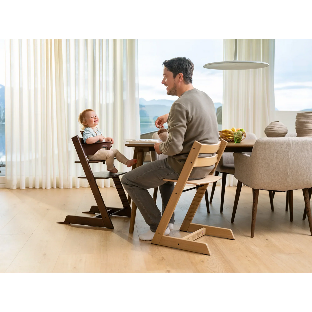 Dad and child enjoy mealtime together in the Stokke Tripp Trapp high chair, sharing smiles at the family dining table.