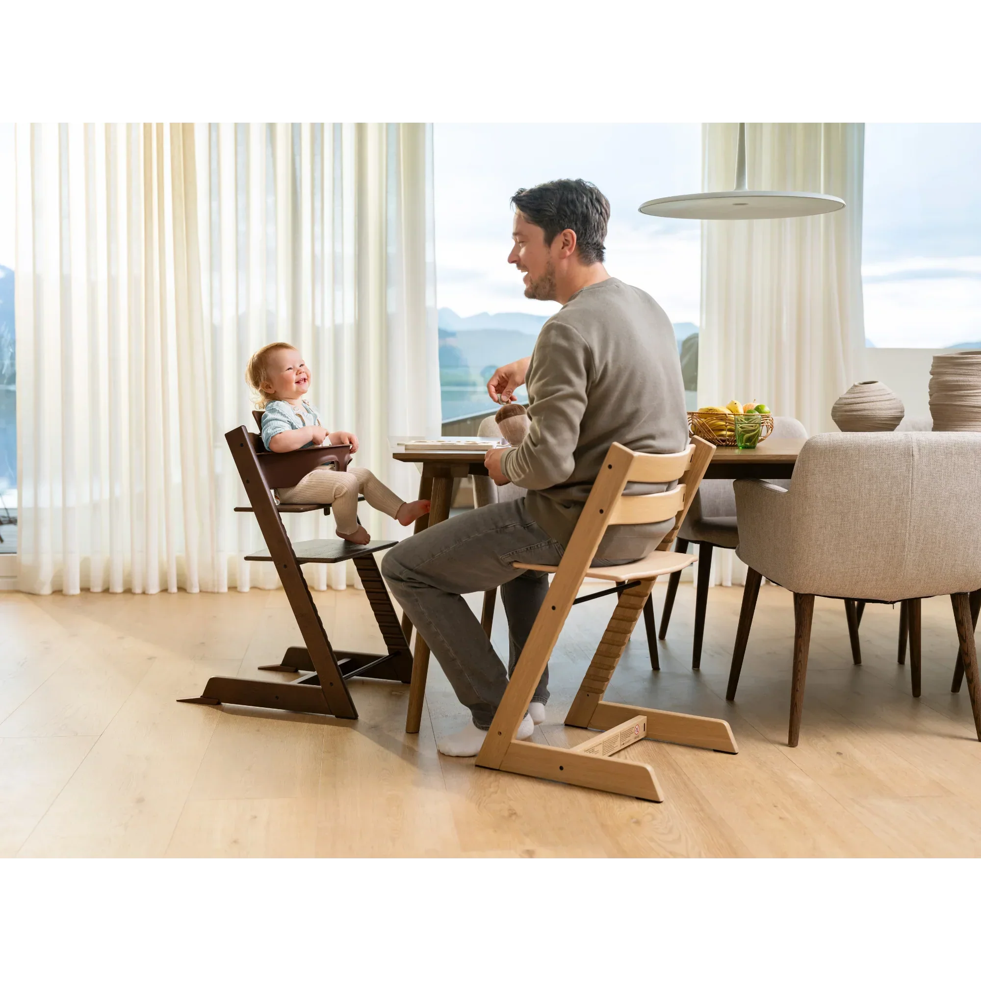 Dad and child enjoy mealtime together in the Stokke Tripp Trapp high chair, sharing smiles at the family dining table.