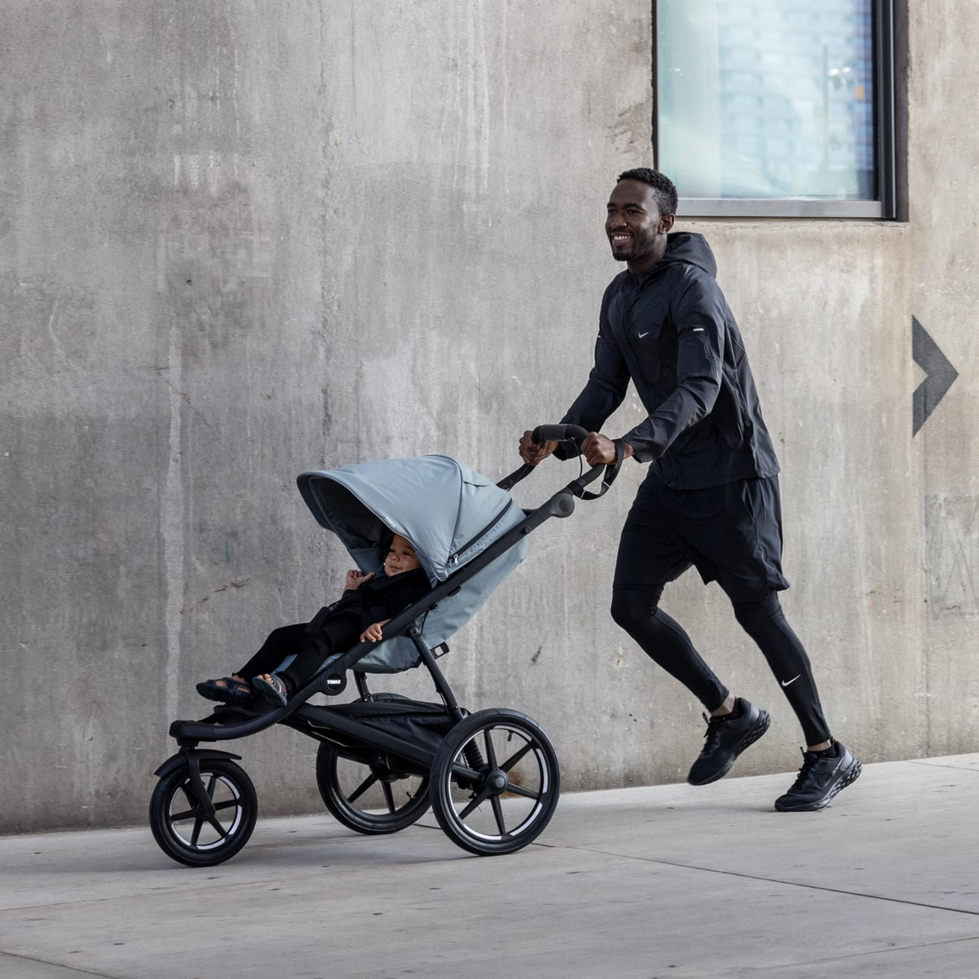 A dad running while pushing the Thule Glide 3 stroller, with his baby ...