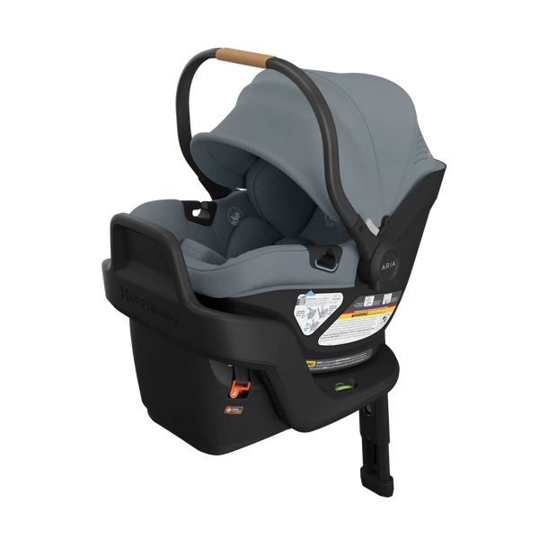  UPPAbaby Aria rear-facing infant car seat in slate grey with a tan leather handle, shown clicked onto its load-leg base with canopy up.
