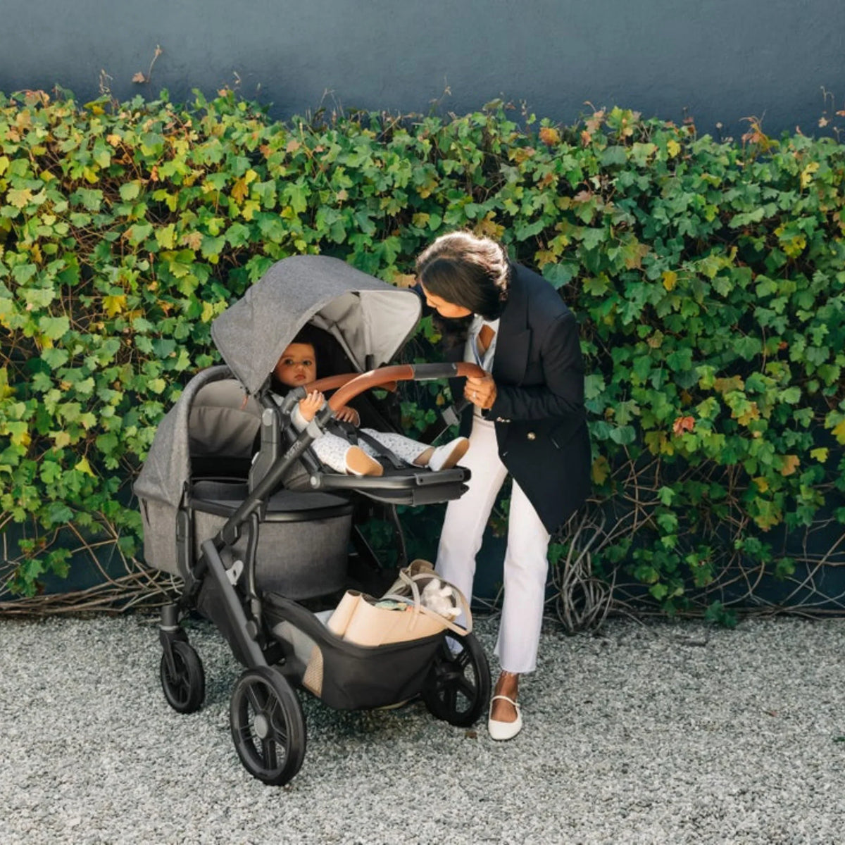 Mom with her baby in the UPPAbaby Vista V3 stroller with the Bassinet attached for comfortable family strolls.