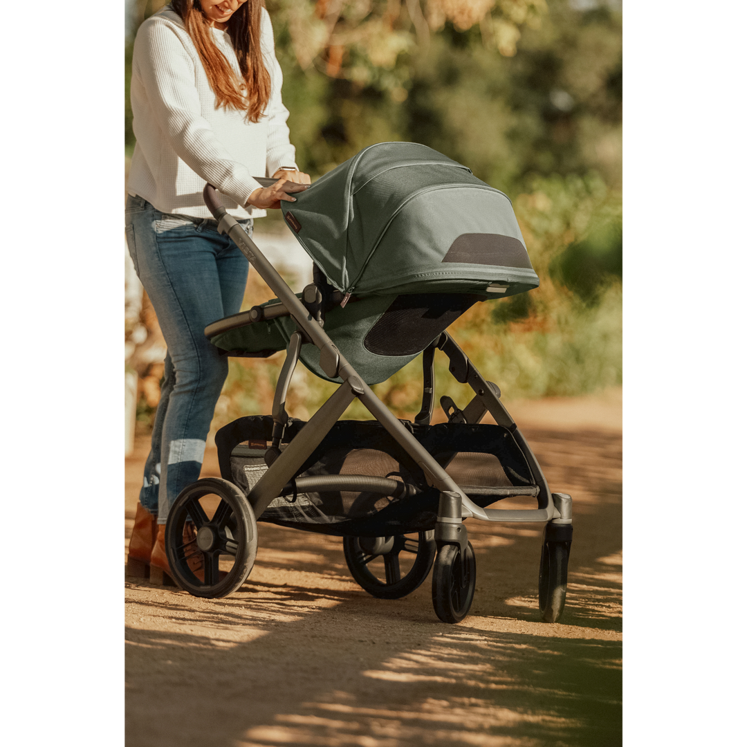 Mom pushing UPPAbaby Vista V3 stroller in a garden, canopy extended to shield her baby from the sun for comfort and protection.