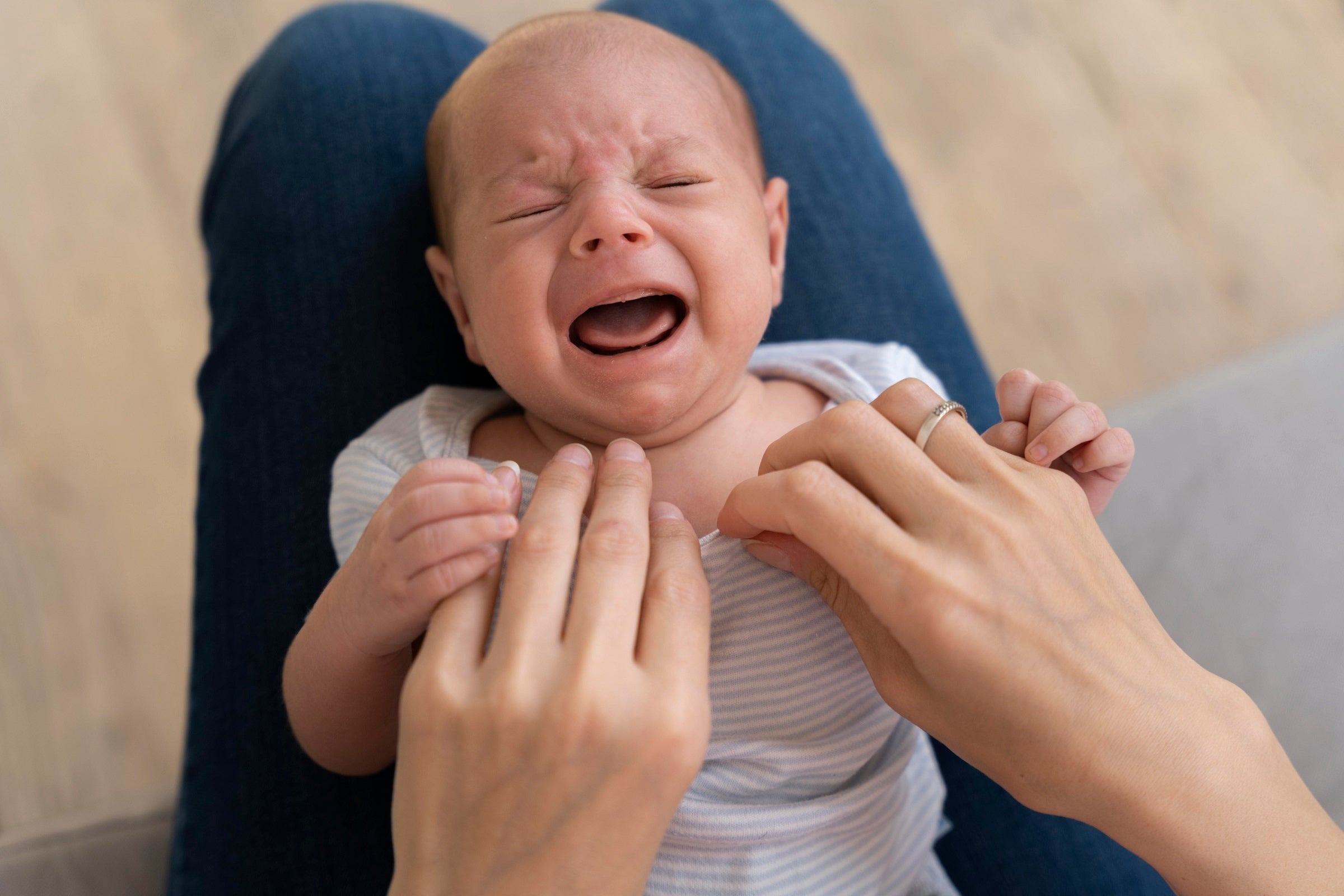 Crying baby displaying signs of sleep regression, with a distressed expression.