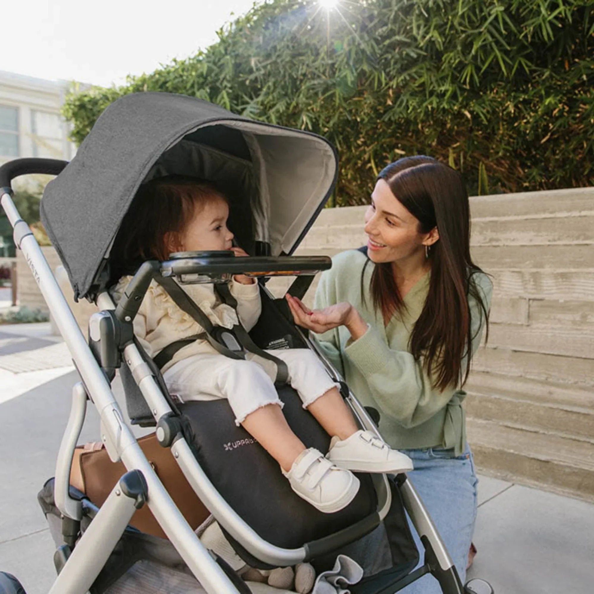 UPPAbaby snack tray attached to Vista V3 while mom smiles beside her child enjoying snacks comfortably on the go  