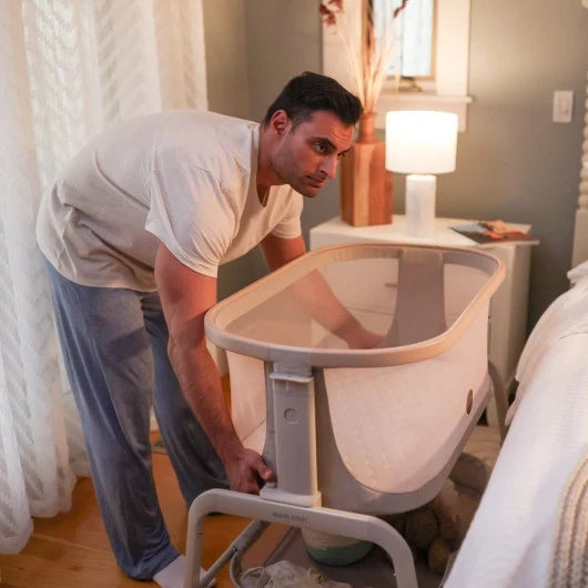 Father setting up the Maxi Lora bedside bassinet next to the bed, creating a safe and convenient sleep space for babies. 