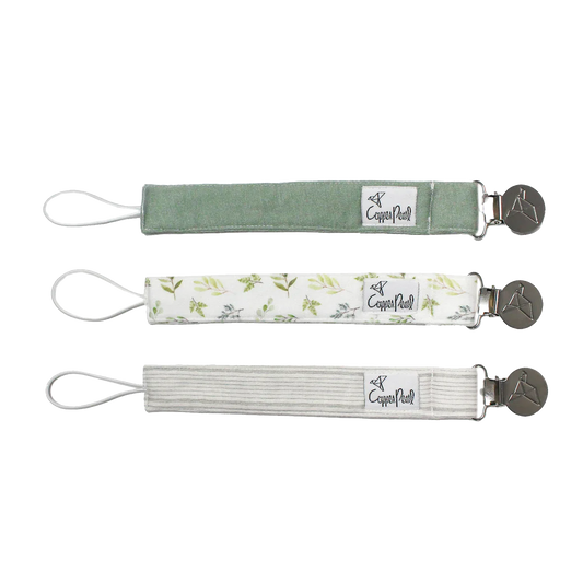 Set of three Suavinex pacifier clips in green, white with patterns, and grey.