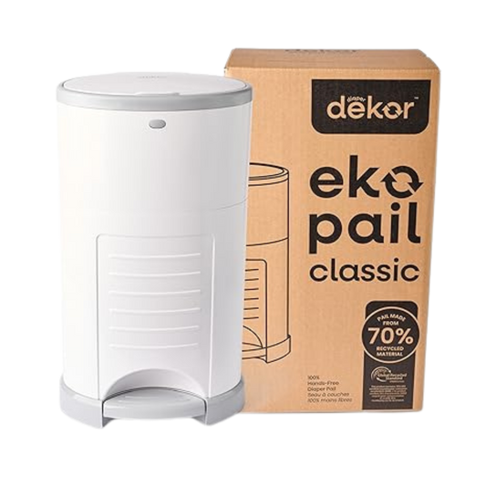 White diaper pail with foot pedal next to its packaging box labeled “Dékor Eko Pail Classic,” designed for hands-free, odor-sealing diaper disposal.