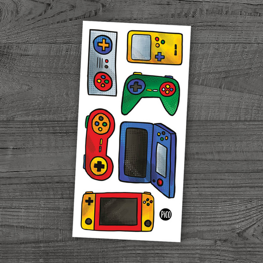 Pico Tatoo Video Games tattoo sheet with six designs including controllers and handheld consoles in red, green, blue, and yellow on wood background.