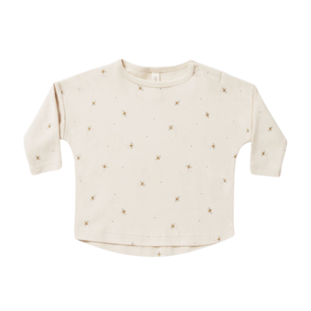 Cream long-sleeve baby top with small scattered beige print and shoulder snaps, shown front-on on a white background for product display.