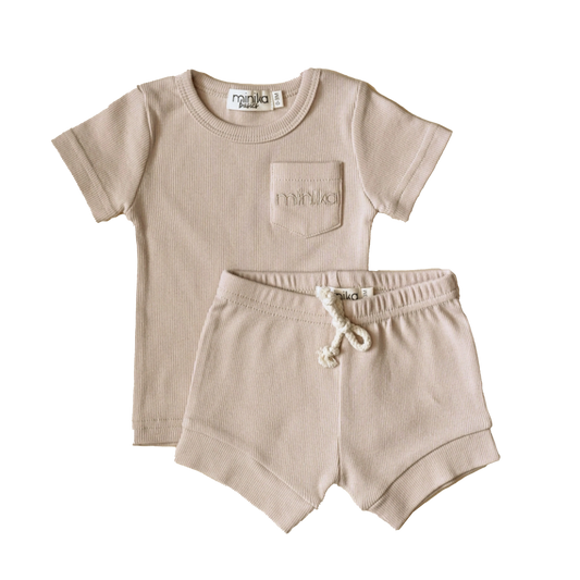 MINIKA cream two-piece set for toddlers featuring a ribbed short-sleeve top with front pocket and drawstring shorts, laid flat.
