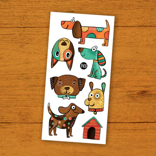 PICO TATOO temporary tattoo sheet featuring seven colorful cartoon dogs and a red doghouse, shown on a wood surface for playful style.
