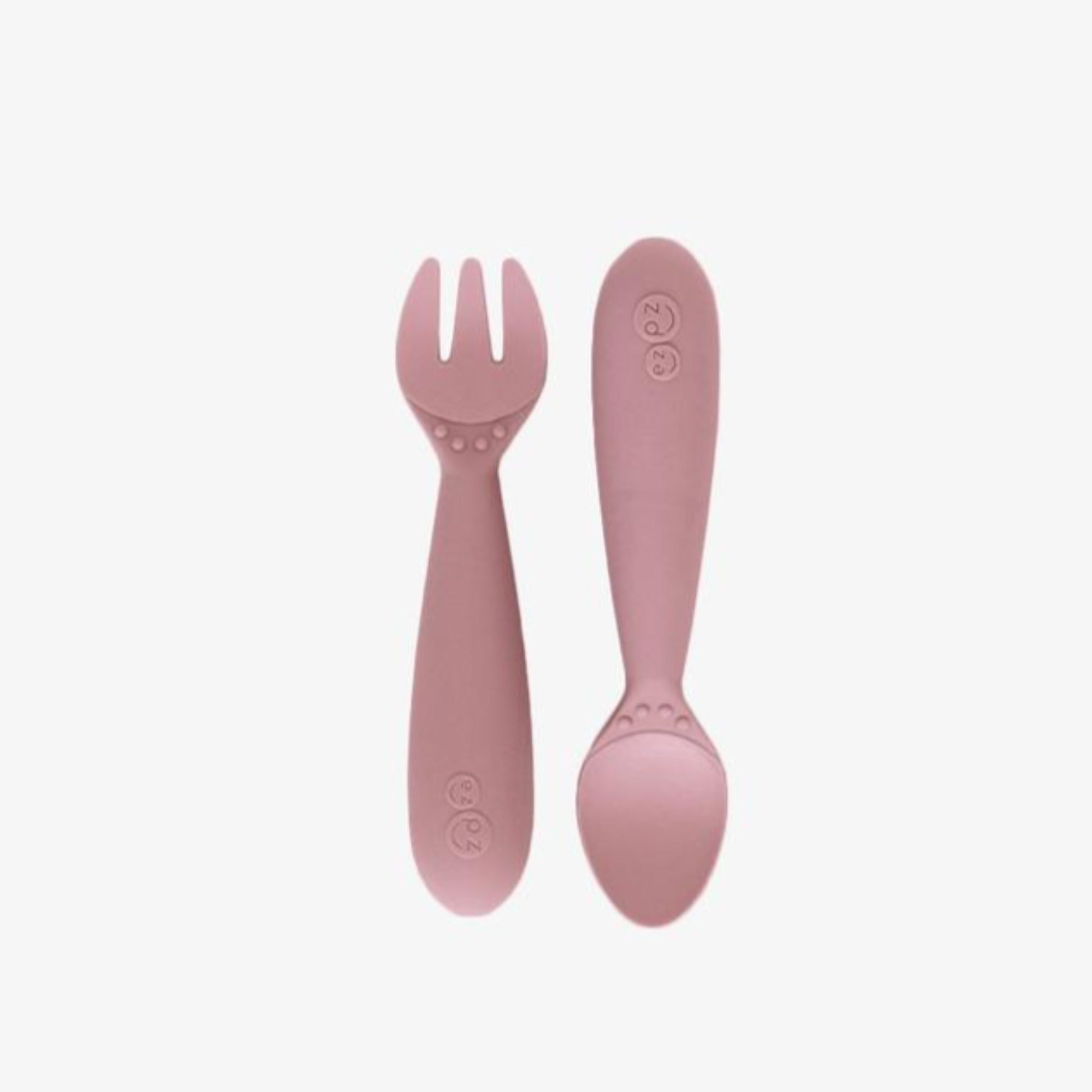 EZPZ Mini Utensils in blush, a silicone fork and spoon set designed for toddlers, shown upright side by side on a white background.