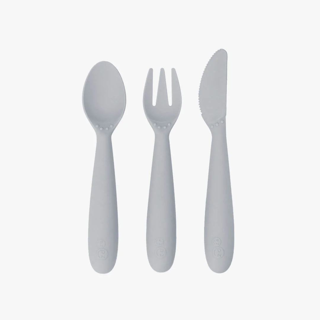 EZPZ Happy Utensils set in pewter grey with spoon, fork, and knife featuring rounded toddler-friendly handles, shown on white background.