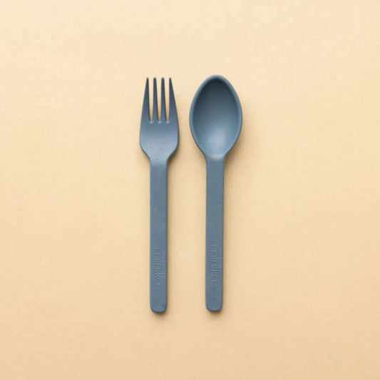 MINIKA mini fork and spoon set in blush, ergonomic silicone utensils designed for toddlers, shown upright side by side on a peach background.